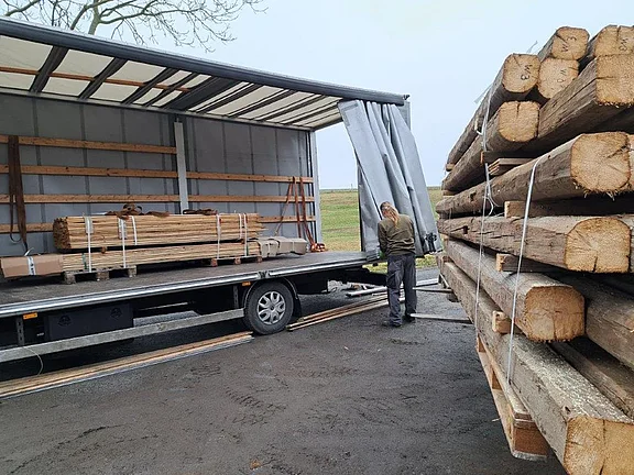 Alte Holzbalken und historische Bauhölzer auf einem LKW für Lieferung