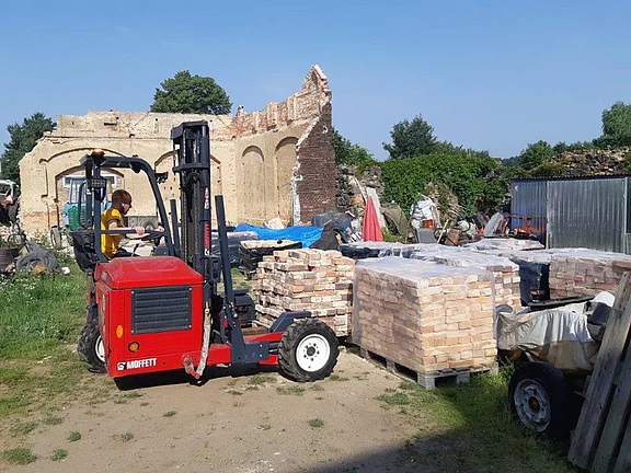Alte Ziegel und historische Baustoffe werden auf einer Baustelle für Transport und Wiederverwendung verladen